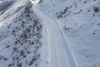 an aerial view of a snow covered road with tracks of skiers and snow skiers