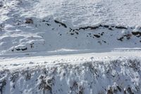 a man riding skis across snow covered ground next to a mountain slope side walk