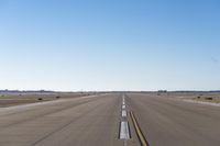 a street with a plane coming in to land in the middle of the distance, and yellow lines running down the street