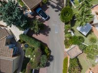 a view down on a residential neighborhood and parking lot from above, looking down onto a parking lot in the middle of it