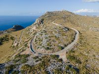 the curve road leads to an ocean view from a high cliff side overlook at rocky coastline and blue water