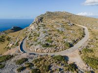 the curve road leads to an ocean view from a high cliff side overlook at rocky coastline and blue water