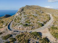 the curve road leads to an ocean view from a high cliff side overlook at rocky coastline and blue water