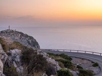 a curving curved curved road on the edge of water near an ocean at sunset time