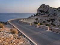 a car is driving down a curvy road on a clear day near the ocean