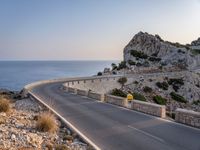 a car is driving down a curvy road on a clear day near the ocean