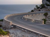 a car is driving down a curvy road on a clear day near the ocean