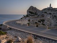 a car is driving down a curvy road on a clear day near the ocean