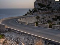 a car is driving down a curvy road on a clear day near the ocean