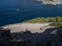 the car is driving on the road near the shore and water with houses and boats