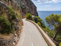 a long paved road on the edge of a cliff overlooking the ocean and a body of water