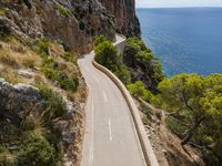 a long paved road on the edge of a cliff overlooking the ocean and a body of water