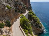 a long paved road on the edge of a cliff overlooking the ocean and a body of water