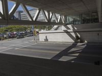 an outdoor area with a walkway and a very wide street filled with cars on the side