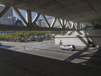 an outdoor area with a walkway and a very wide street filled with cars on the side