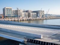 a train is seen traveling across the bridge that's crossing the water into an office building next to a street