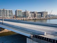 a train is seen traveling across the bridge that's crossing the water into an office building next to a street