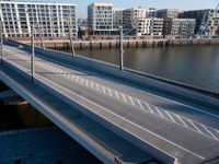 a train is seen traveling across the bridge that's crossing the water into an office building next to a street