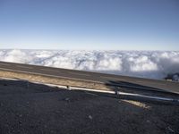 two lanes that are connected to each other with clouds above them on top of the mountain