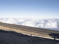 two lanes that are connected to each other with clouds above them on top of the mountain