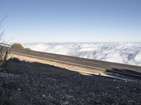 two lanes that are connected to each other with clouds above them on top of the mountain