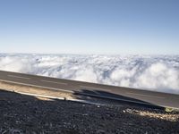 two lanes that are connected to each other with clouds above them on top of the mountain