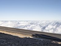 two lanes that are connected to each other with clouds above them on top of the mountain