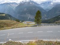 a curved road leading to the mountains with a view of the valley in the background