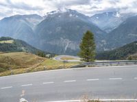 a curved road leading to the mountains with a view of the valley in the background