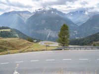 a curved road leading to the mountains with a view of the valley in the background