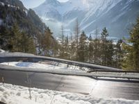 a road through the middle of some snow covered mountains and woods, on a cold day