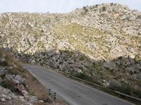 a black and white motorcycle is driving down the winding road on a mountain road near rocks