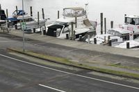 a street next to a river that has parked boats on it and a car on the side