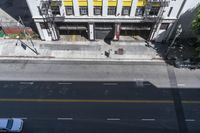 an overhead photo of a yellow building next to a street with cars passing by it