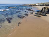 a beach with rocks and water in a sandy area next to the ocean and several other animals