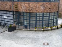 a tall brick building sitting behind a street curb covered in traffic barrier barriers and parking spaces