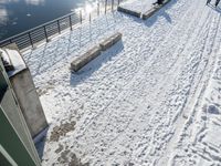 a skiier riding over the top of a ramp on a snowy day over a lake