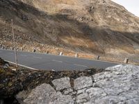 a man riding a white motorcycle on a road next to some mountains near a rock