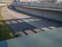 a skateboarder riding on a cement ramp next to a city street under a bridge