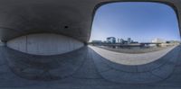 a distorted view of a city with buildings in the background and fish eye lens in foreground