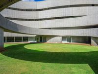 the large circular room has grass and greenery around it and is shaped like a curved ramp