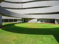 the large circular room has grass and greenery around it and is shaped like a curved ramp