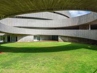 the large circular room has grass and greenery around it and is shaped like a curved ramp