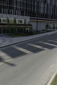 a bike rider rides on the empty city street by a building on a sunny day