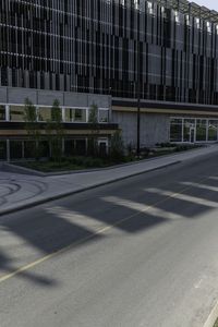 a bike rider rides on the empty city street by a building on a sunny day