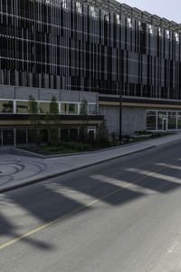 a bike rider rides on the empty city street by a building on a sunny day