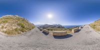 a 360 degree photo of the mountains and the ocean on a sunny day showing some benches for sitting