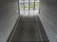 the inside of a building with concrete walls and flooring and windows on either side of them