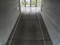 the inside of a building with concrete walls and flooring and windows on either side of them