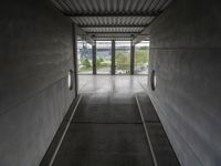 the inside of a building with concrete walls and flooring and windows on either side of them